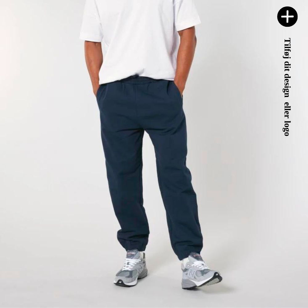 En person iført navy bukser og hvide sneakers. Tilføj dit design eller logo.