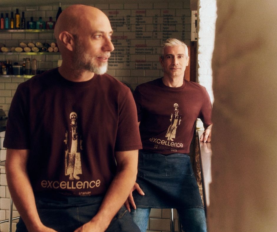 To mænd iført t-shirts med firmatryk i deres cafee