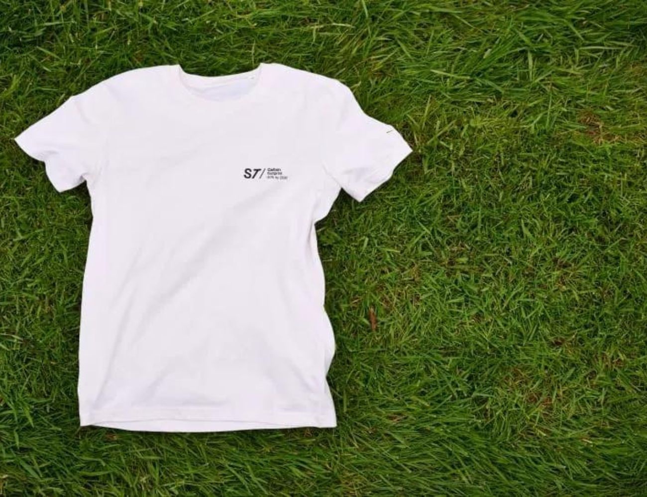T-shirt med logo ligger på en grøn græsplæne